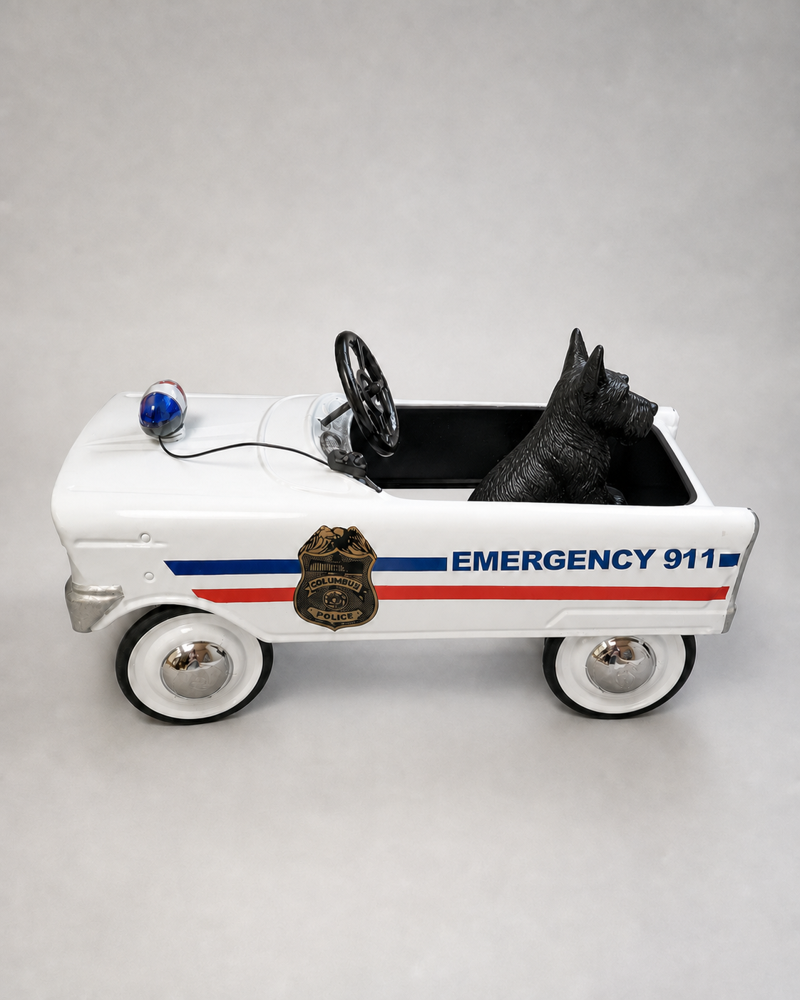 White children’s pedal car marked Emergency 911 with a Columbus Police badge decal, red and blue stripes, whitewall tires and a blue roof light