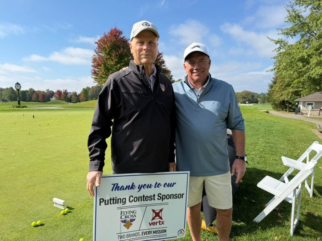 Two golfers with the Flying Cross and Vertx putting contest sign