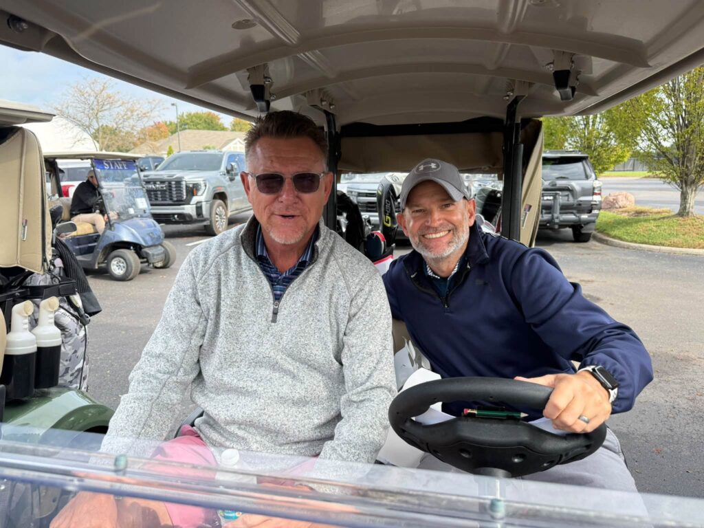 Two golfers in their cart, ready to head out
